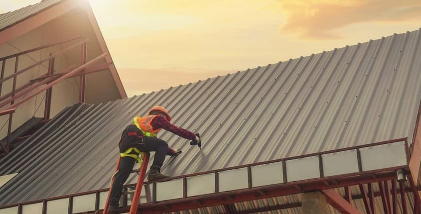 NIR-August-Blog-1 Roofing professional installing a metal roof in the sun