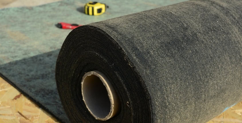 What is Roof Underlayment_ February Blog 3 Thick roll of roofing material on a slab of wood