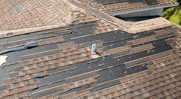 Commercial apartment building missing and damaged asphalt shingle roofing